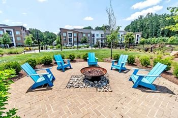 Outdoor fire pit with adirondack chairs and landscaping